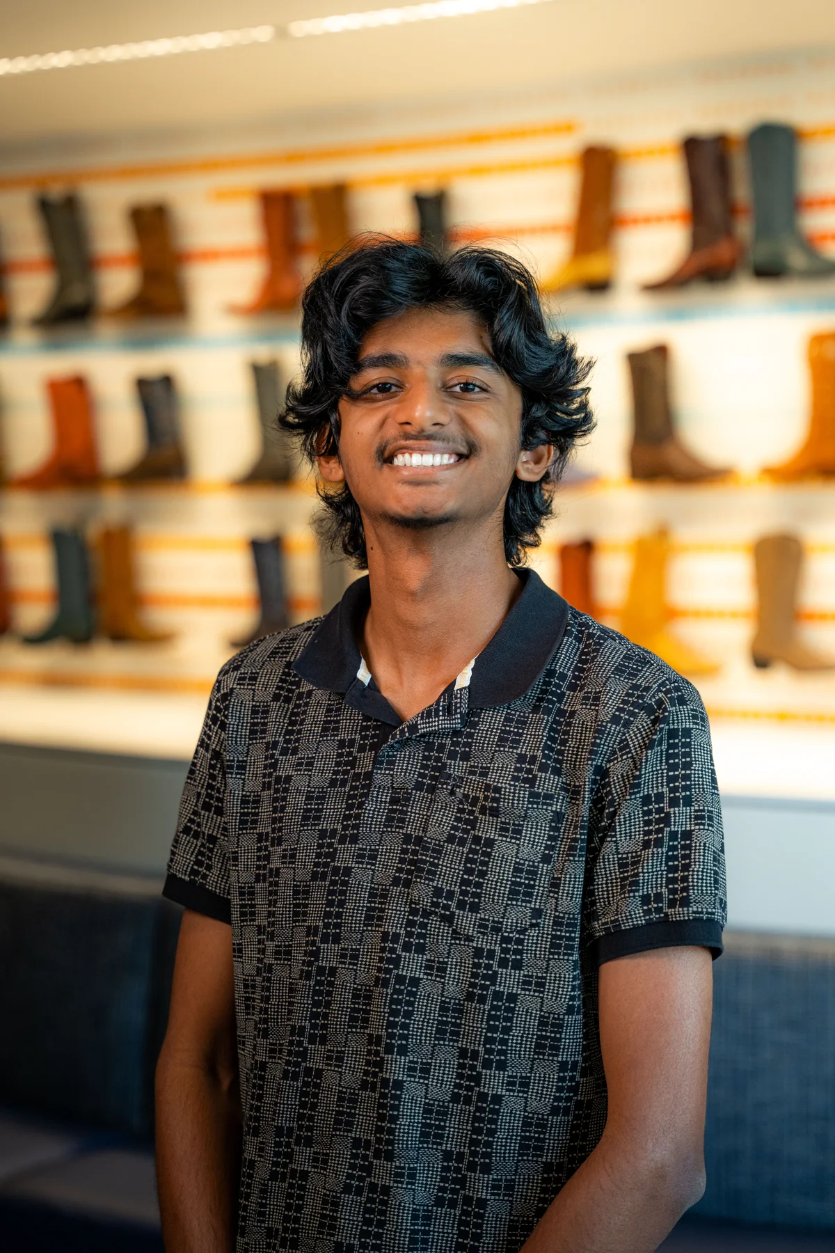 Aniketh smiling in front of a display of boots